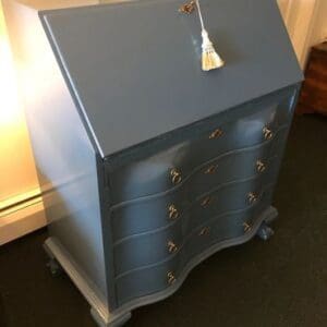 A blue desk with gold handles and knobs.