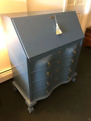 A blue desk with gold handles and knobs.