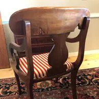 A wooden chair with red and white striped seat cushion.